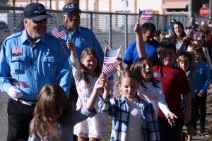 Moundsville Veterans Honor Guard members and Glen Dale Elementary students wave American flags while walking in the school’s Veterans Day Parade.