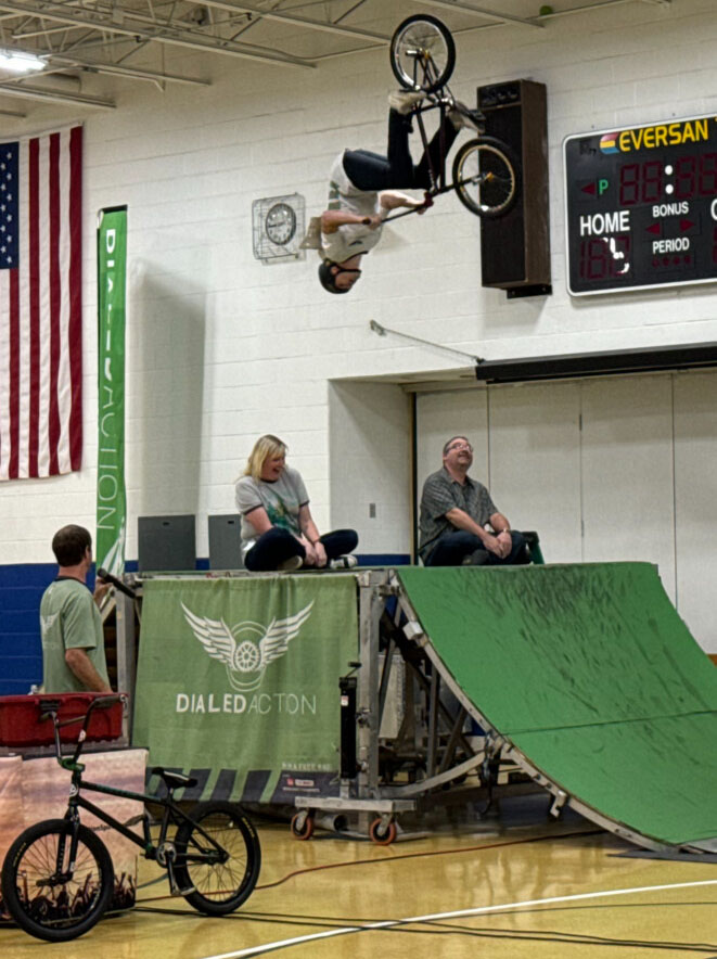 Cameron Elementary School nurse Melissa O'Donnell and Cameron Elementary School aide Jason Courtwright volunteered to sit on the ramp while a stunt cyclist performed a trick during the BMX Bike Show.