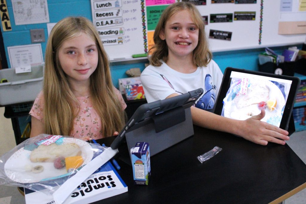Pictured from left: Central Elementary 5th graders Arianna Cepeda and Karlie Anderson use their iPads to do a mold terrarium experiment to discover how various foods decompose at a different rate. They take daily pictures to record and compare the changes.