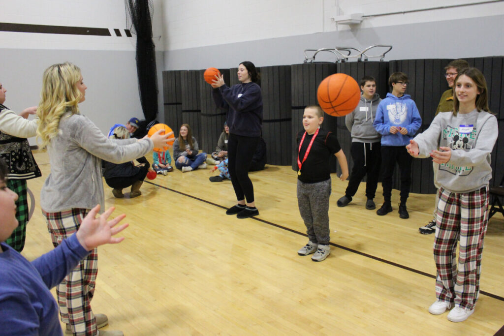 Student athletes and peer tutors pass basketballs back and forth.  