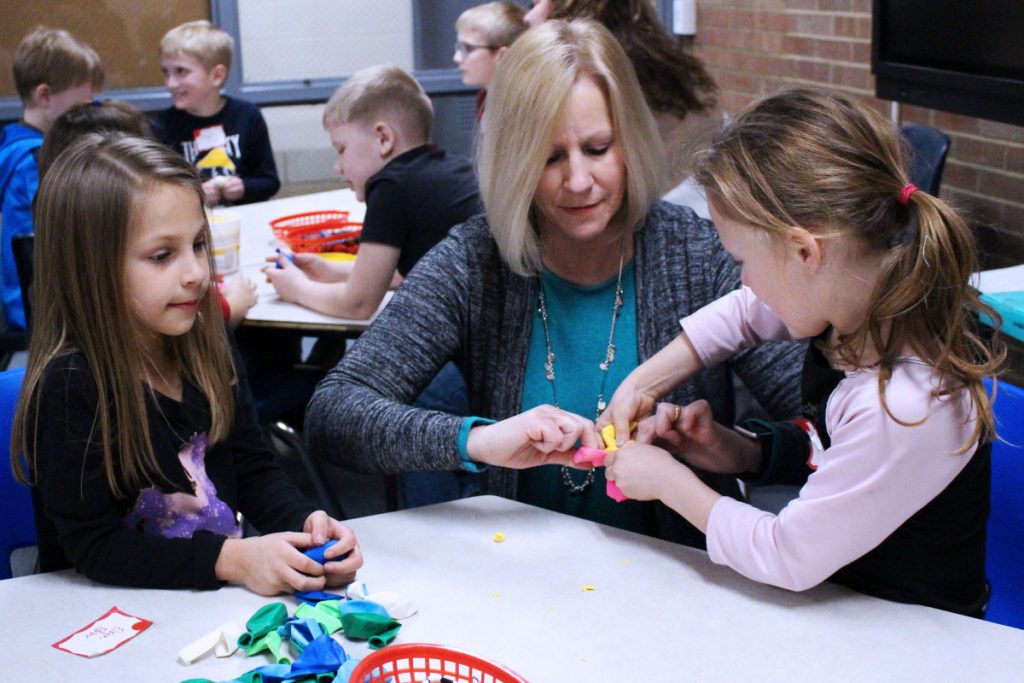 Glen Dale Elementary second grade teacher Tami Scollick, center, helps kindergartners Elaya Farber, left, and Ady Young stuff paly clay into a balloon to make stress balls at the Family Mindfulness Night.