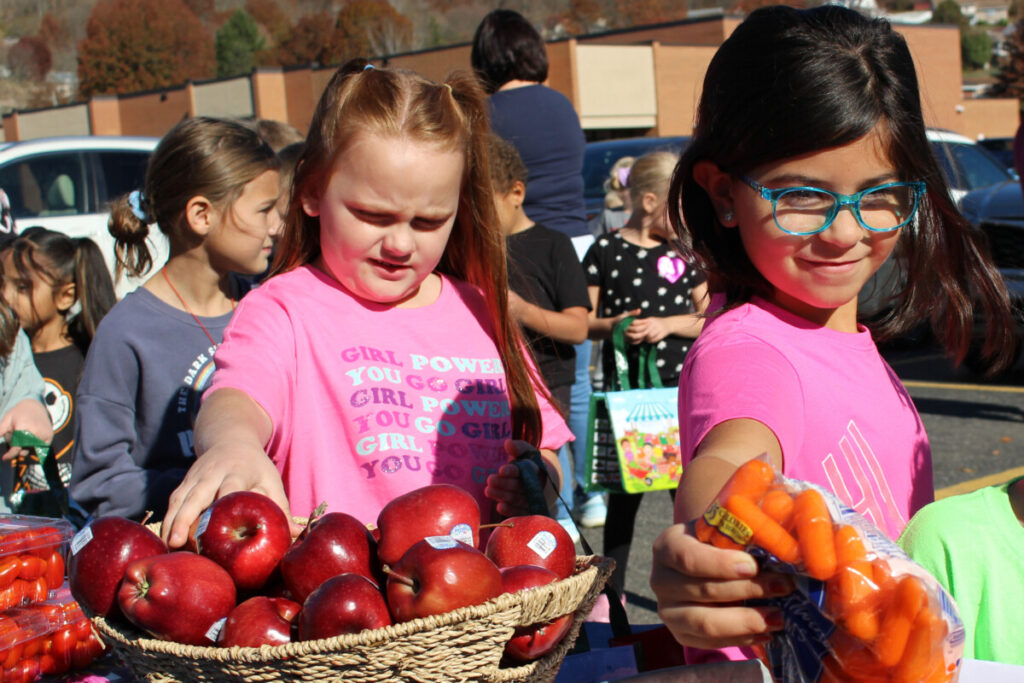 Kids pick out fruits and vegetables to put in their shopping bags.