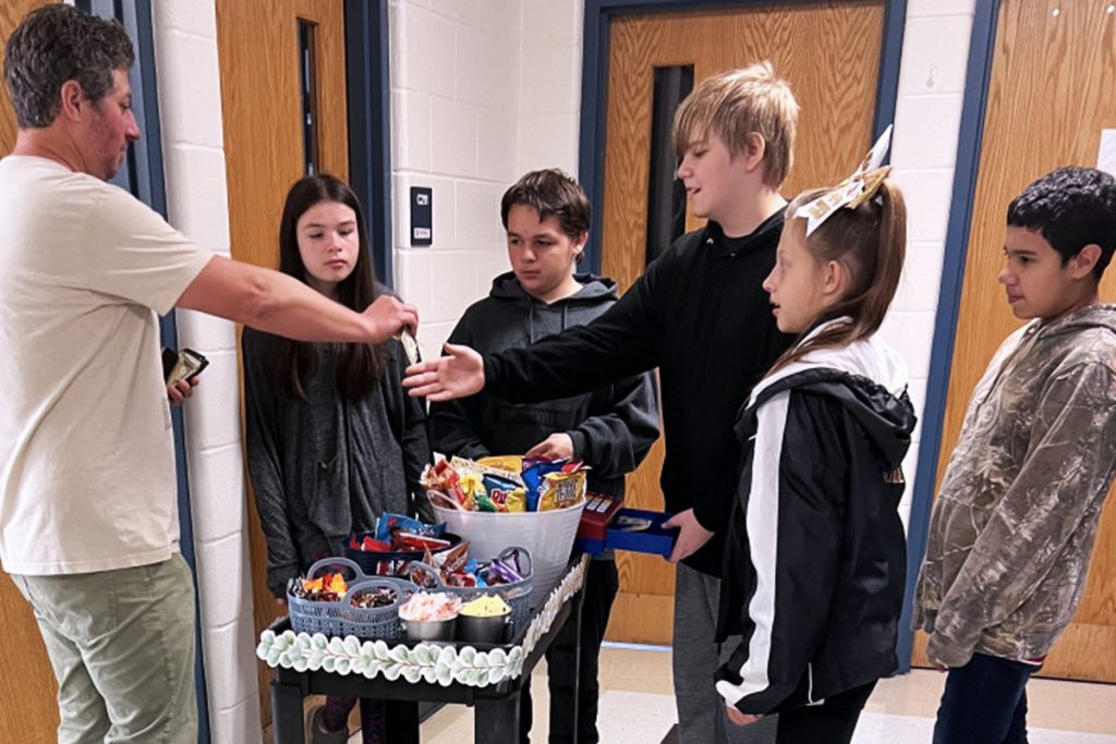 MMS student Steven Lashare, center, makes change for Mr. Myers's order from “The Cool Beans Cart” while his classmates, from left, Brookelyn Yocum, Luis Lopezwait Alex Reynolds and Hayden Slaughter-Carvoo wait for the transaction to be completed. 