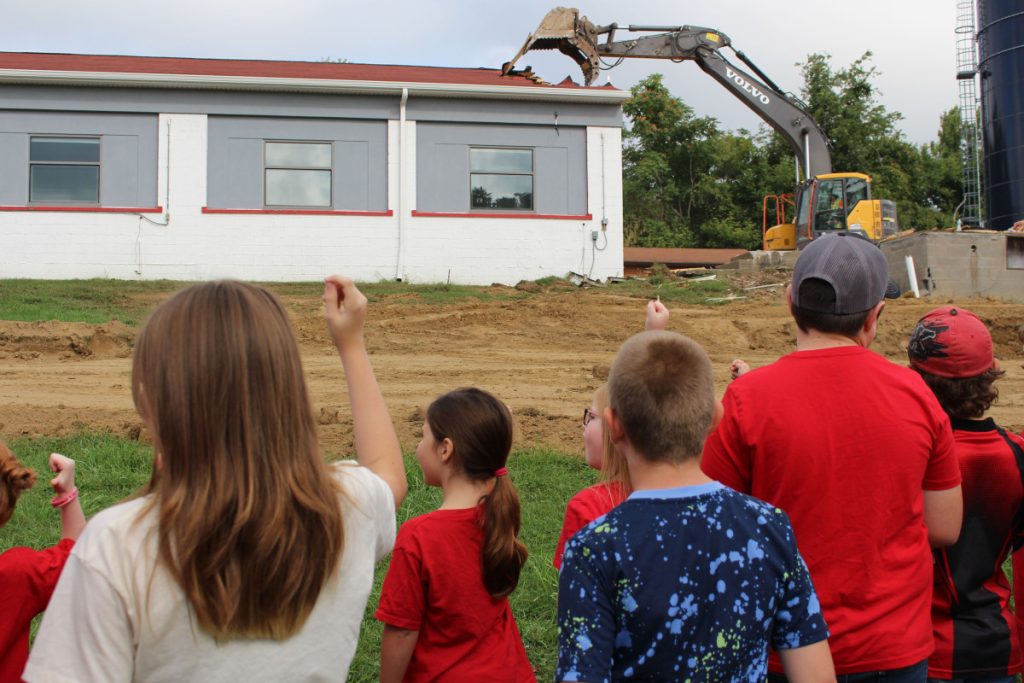 Sand Hill Elementary students wave goodbye to their old school while chanting "tear it down!"