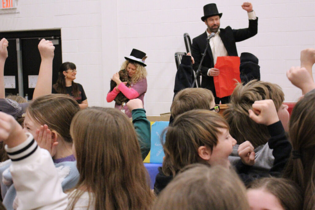 WLES students cheer when they hear Wildcat Wally predict an early spring. WLES PE teacher Michael Grimm and WLES Speech Therapist Becky Hinerman are in the background with Wildcat Wally.